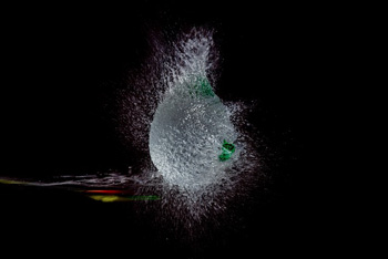 arrow piercing exploding balloon filled with water on black background