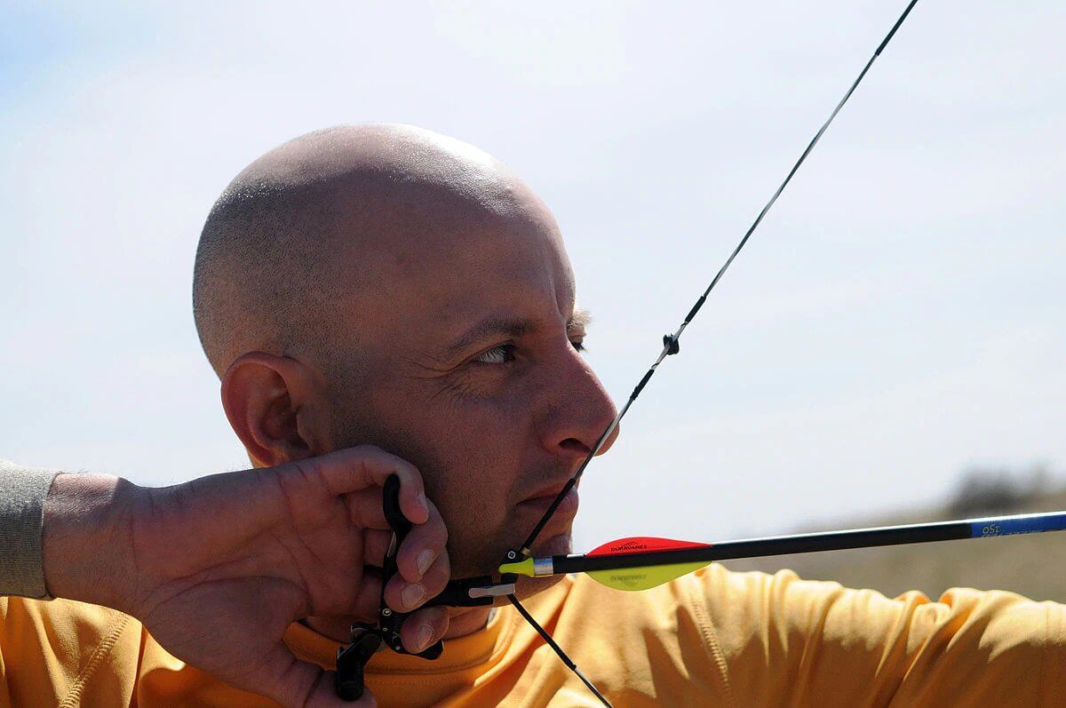 man aiming a bow and arrow