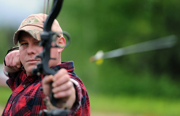 a man firing a compound bow with sights