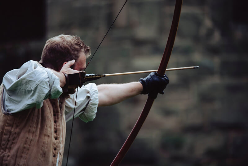 man shooting a target using longbows