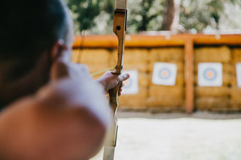 selective focus of man aiming arrow at target