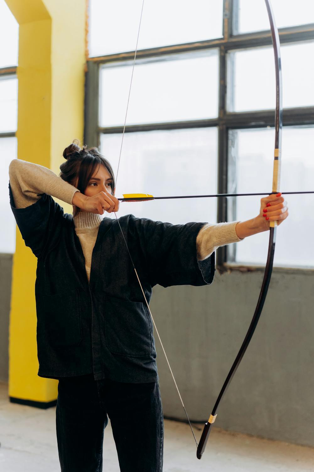 A woman in black drawing a traditional bow