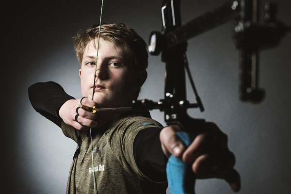 young man using release aids with a compound bow